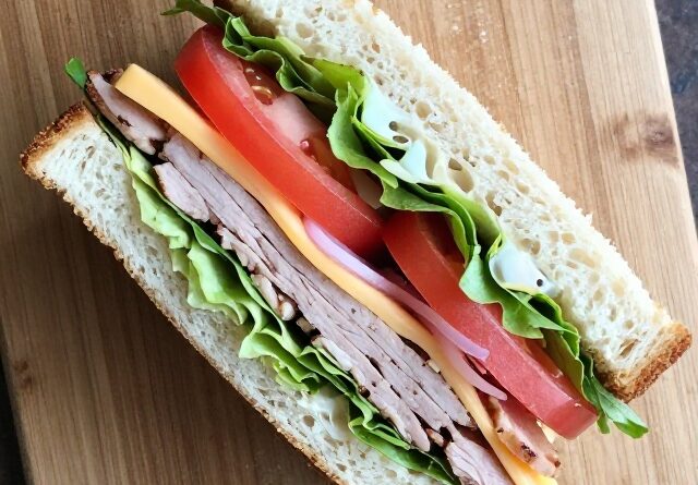 Classic sandwich cut diagonally showing layered fillings on a wooden board