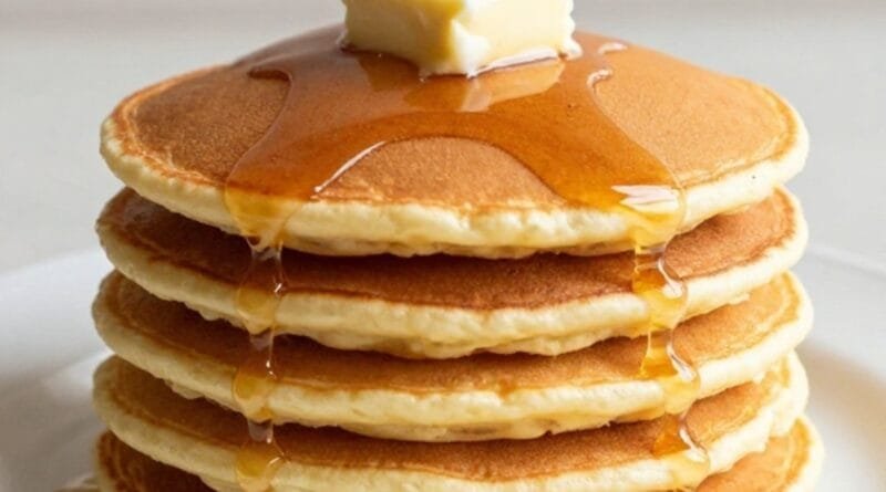 Stack of golden hotcakes topped with butter and syrup