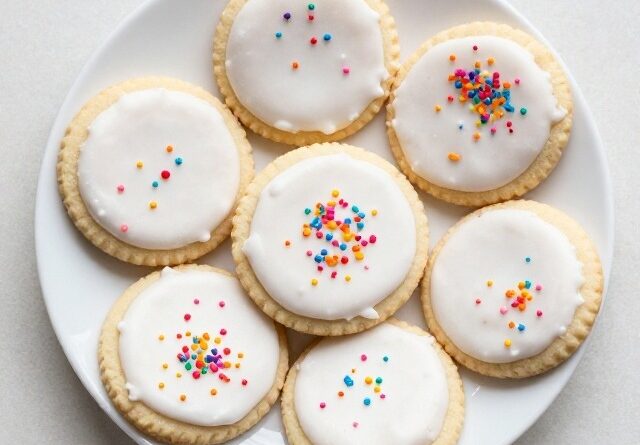 Sugar Cookies Recipe with white icing and colorful sprinkles on a plate