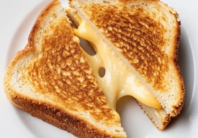 Golden grilled cheese sandwich cut in half showing melty cheese pull
