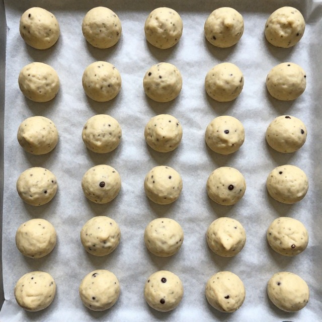 Chocolate chip cookie dough balls arranged on a parchment-lined baking sheet ready to chill, overhead angle, no text, no labels, no background drinks or glasses of liquid