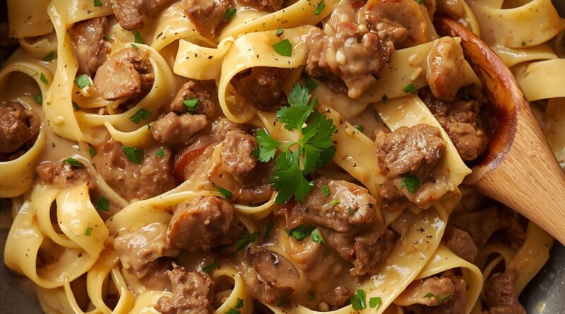 Ground beef stroganoff recipe in a skillet with wide egg noodles and creamy sauce