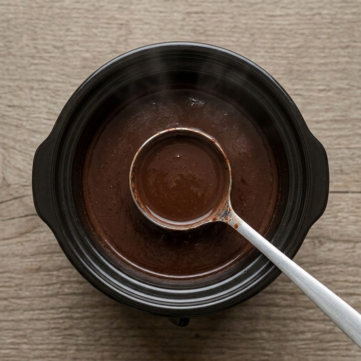 Slow cooker filled with cocoa and a ladle