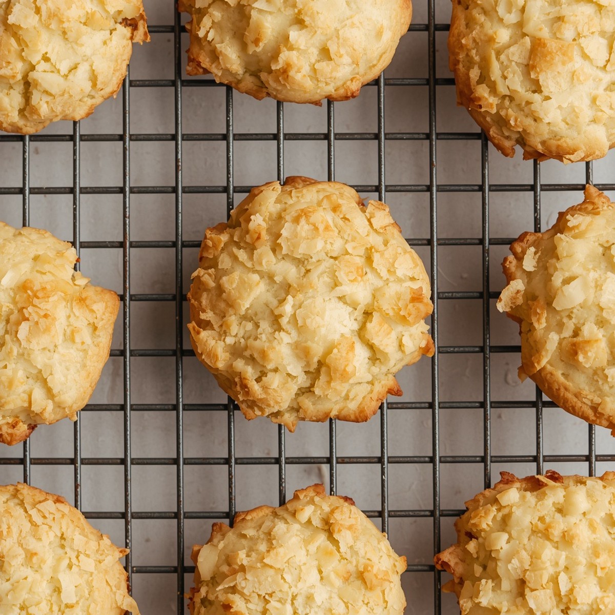 Baked coconut cookies cooling on a wire rack, golden edges visible, no text or branding